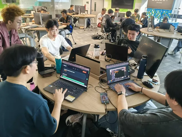 Teams of delegates from Singapore and Hong Kong working at laptops during a Capture-the-Flag cybersecurity competition in a modern indoor venue