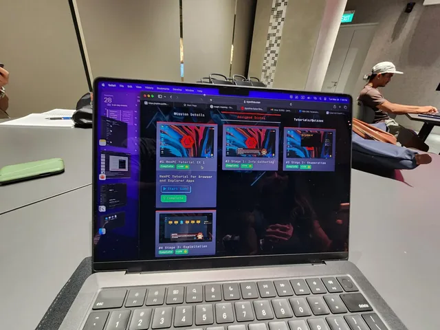 Laptop displaying cybersecurity hacking interface at a workshop table with adult learners in background