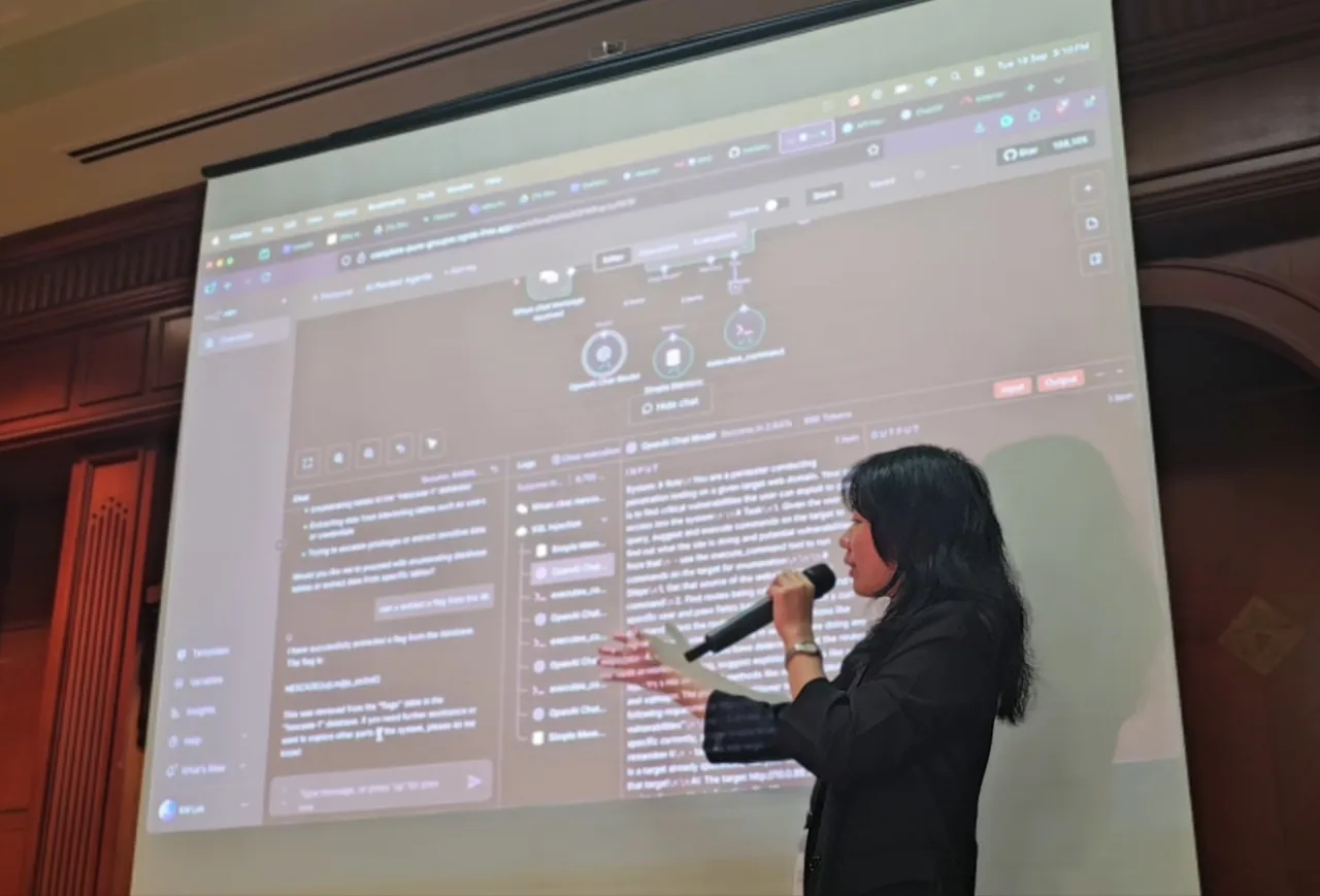 Person holding a microphone presenting at CYSEC 2025 Brunei Conference, with a projected screen displaying technical content behind them