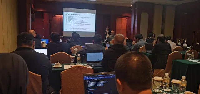 A presenter conducts a workshop at CYSEC 2025 Brunei Conference, with attendees seated at tables facing a projection screen in a hotel conference room