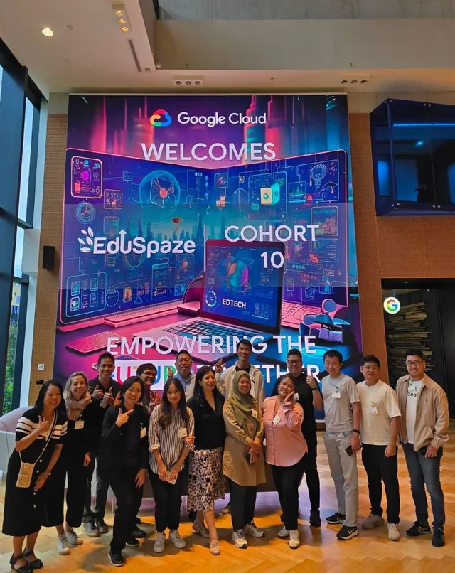 Group of people standing in front of a large digital display showing Google Cloud welcoming Eduspaze Cohort 10