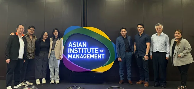 Ten people standing in a line next to the illuminated Asian Institute of Management logo at the launch event