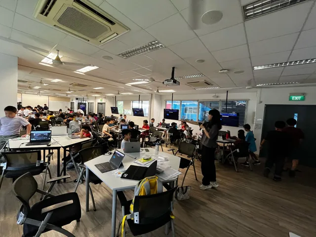 Upper primary students working at laptops and tables during the AgentHex Cybersecurity Bootcamp in a bright classroom with instructors circulating