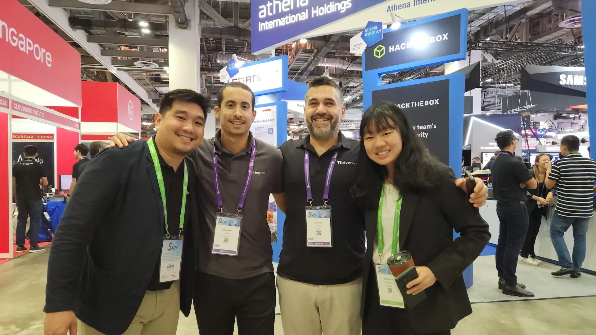 Four people wearing conference badges stand together at Govware 2024 exhibition, with various company booths visible in the background